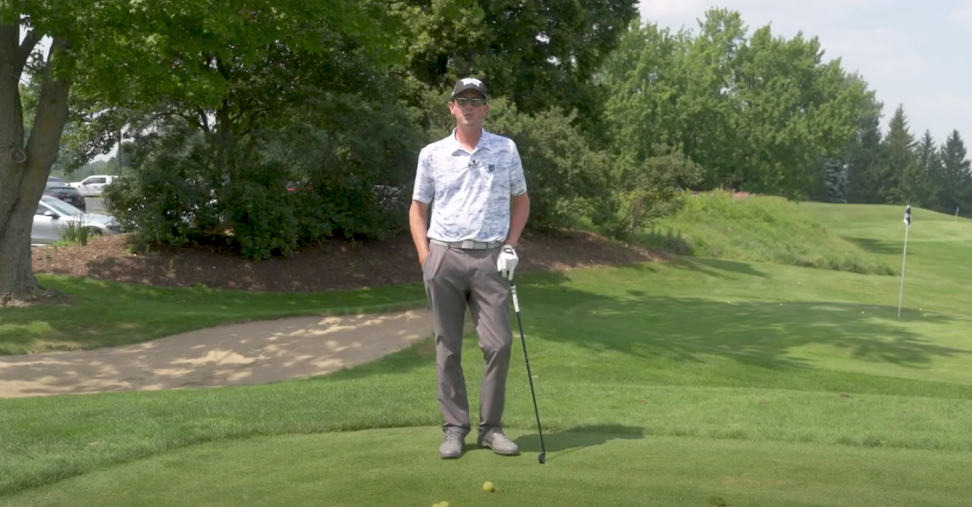 Man on a golf course leaning on a golf club.