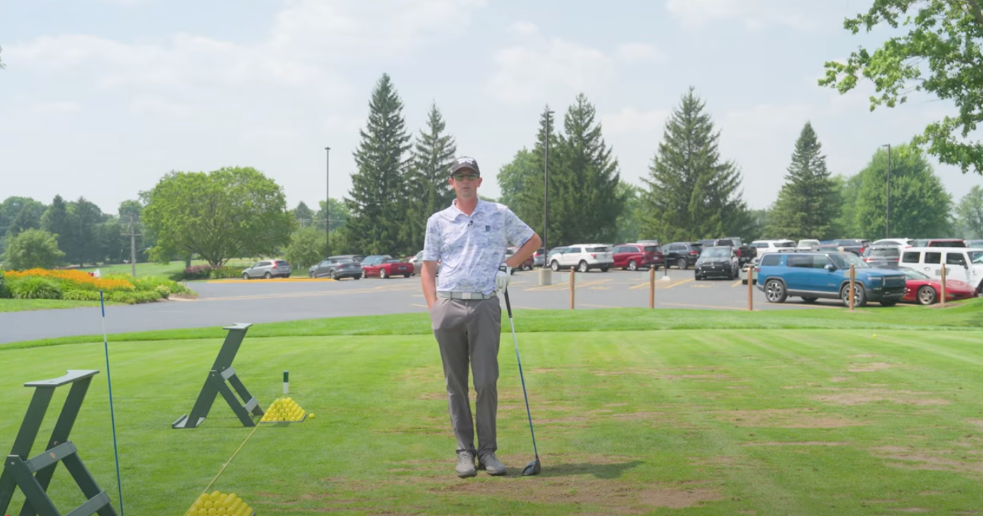 Man on a golf course leaning on a golf club.
